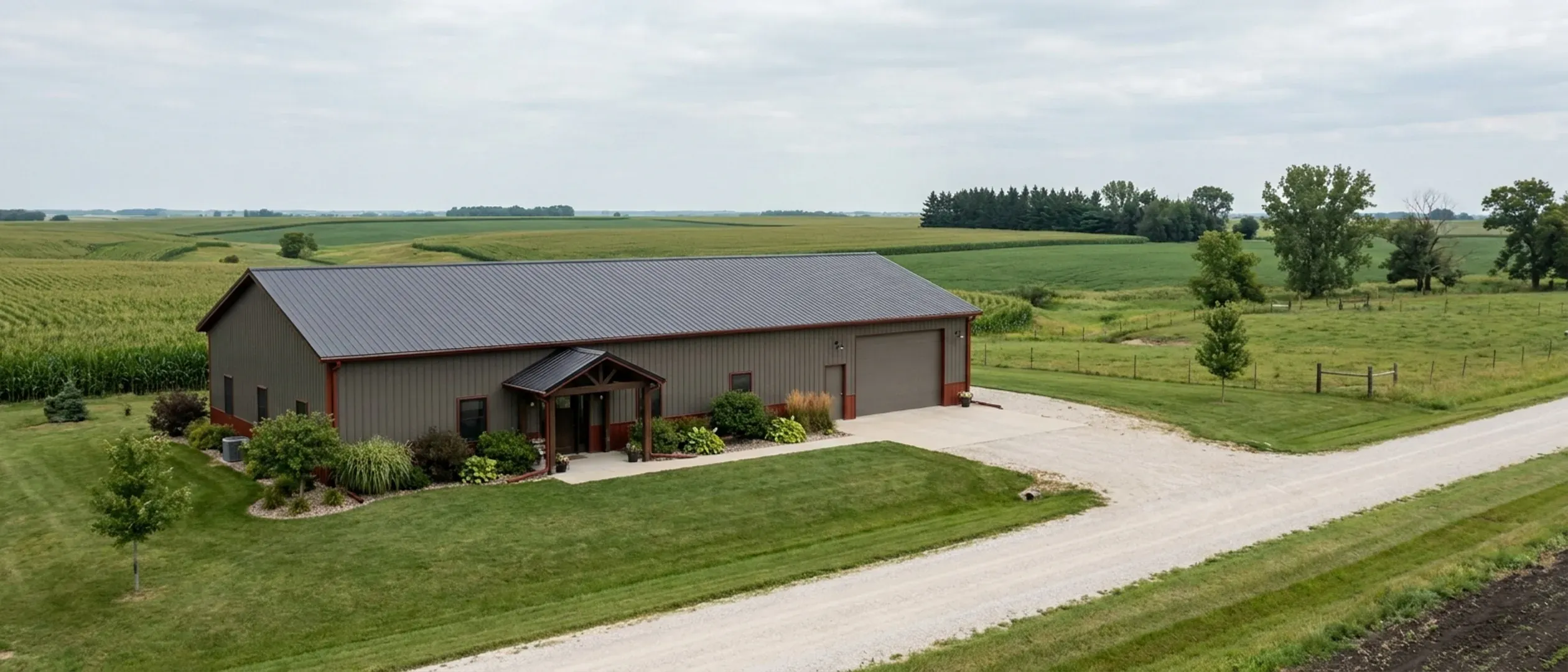 A completed barndominium with a covered entry porch and an attached shop bay, photographed in flat overcast daylight.